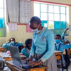 A pupil demonstrates to the class using a laptop, projected on the wall.